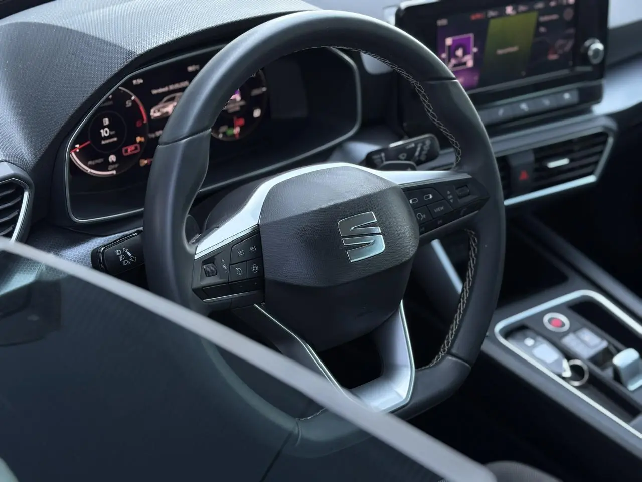 Vue rapprochée du volant cuir multifonction et du tableau de bord numérique du SEAT LEON gris argent 2024.