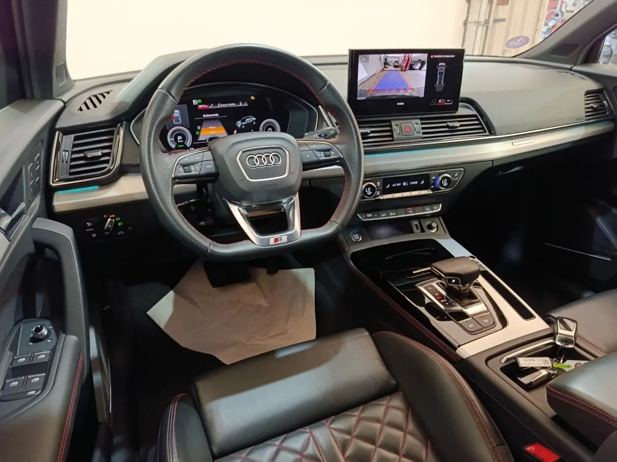 Vue intérieure de l'Audi Q5 2023 hybride rechargeable, avec tableau de bord numérique et volant sport en cuir noir.