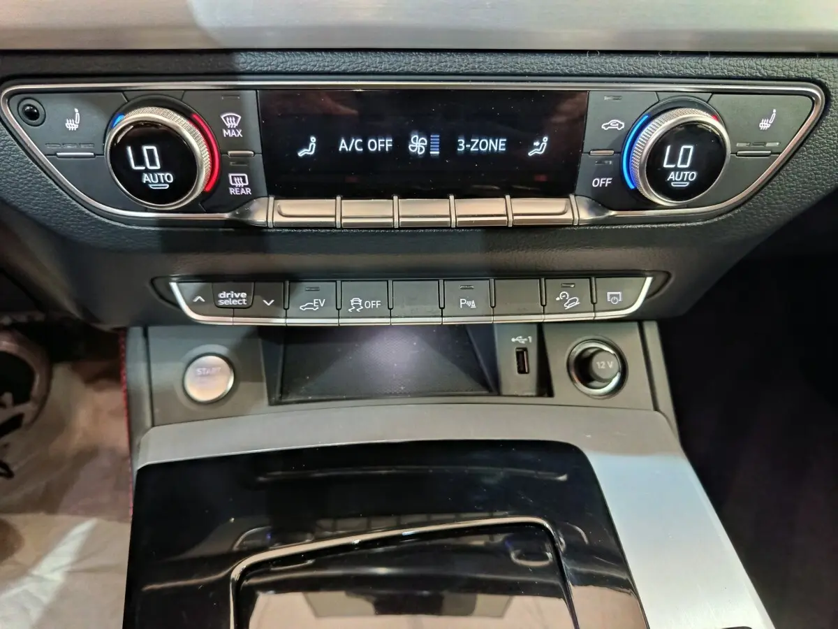 Vue rapprochée du tableau de bord de l'Audi Q5 2023 hybride rechargeable, montrant la climatisation et les commandes centrales.