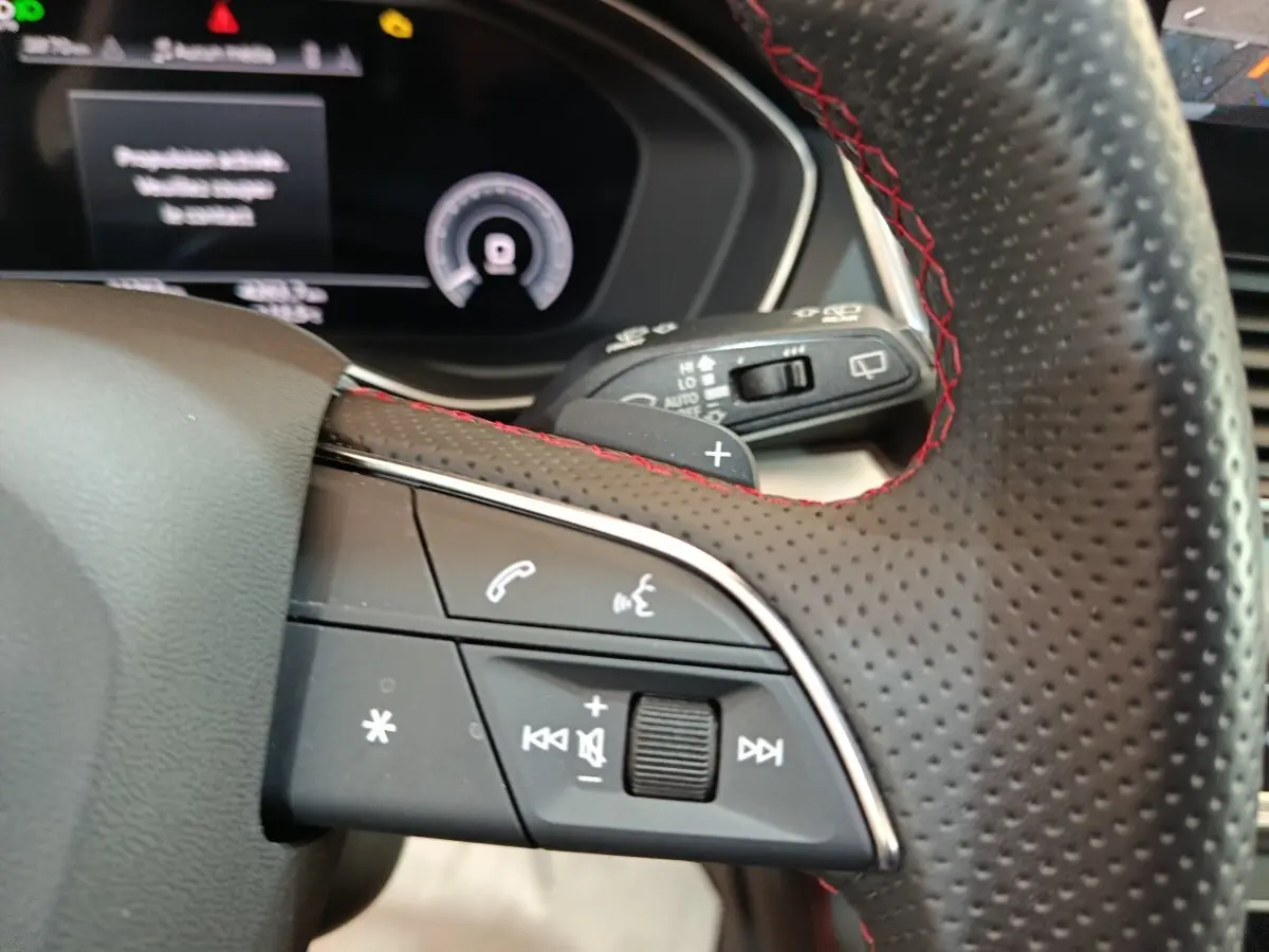 Gros plan sur le volant perforé avec surpiqûres rouges de l'Audi Q5 2023 hybride rechargeable, côté gauche.