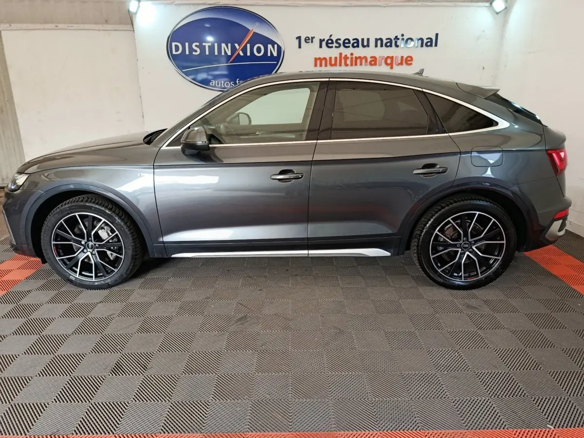 Audi Q5 gris clair 2023 hybride rechargeable, vue profil côté gauche avec jantes noires et détails chromés.
