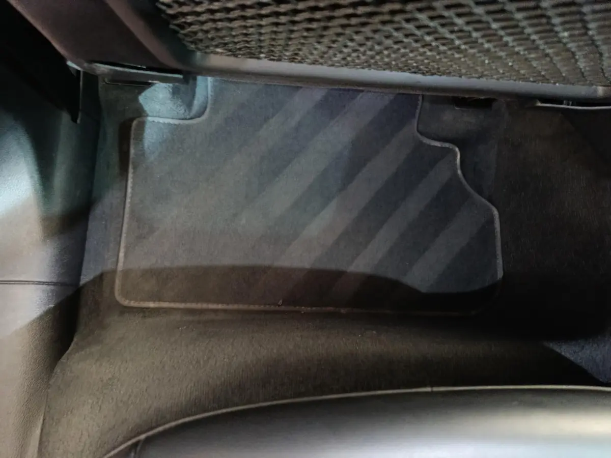 Vue rapprochée du tapis de sol noir côté passager arrière d’un Audi Q5 gris clair hybride rechargeable 2023.