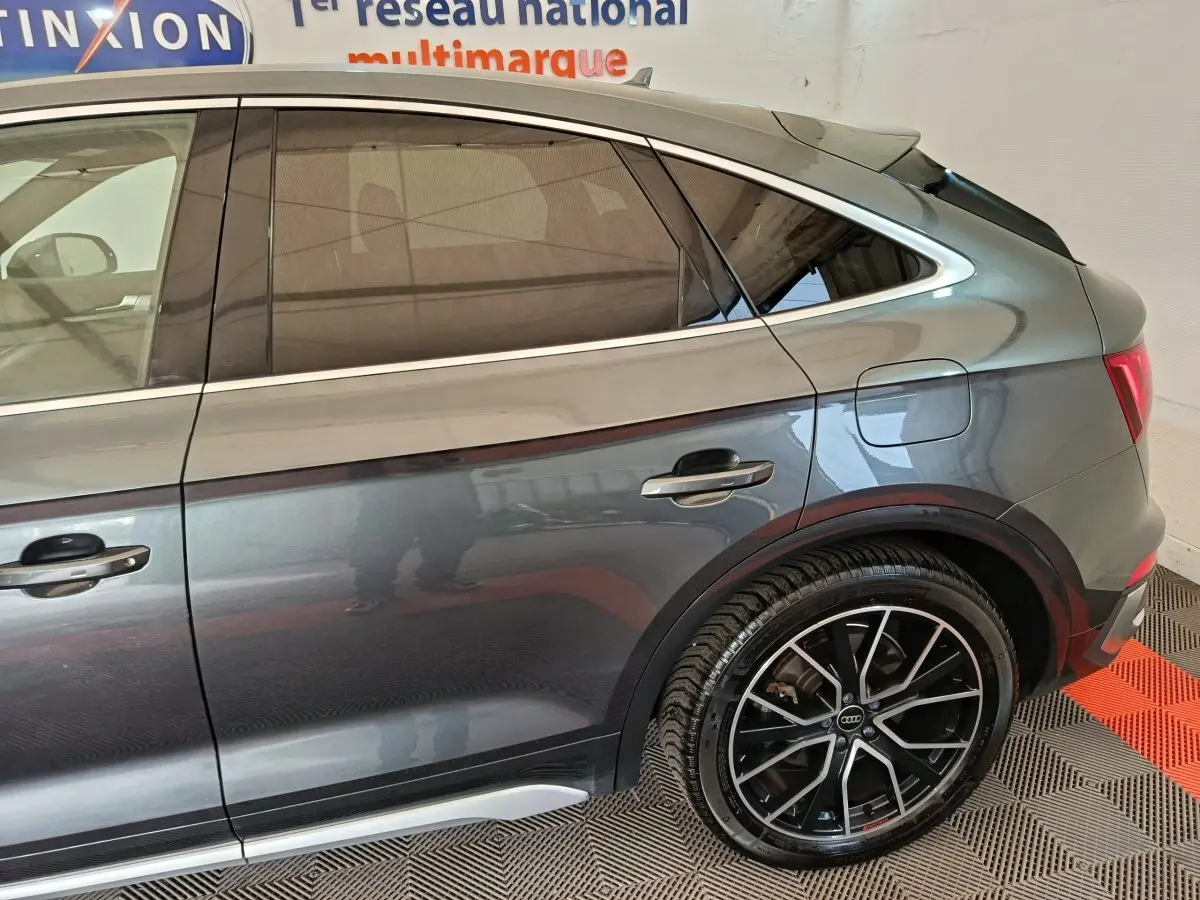 Vue latérale droite d’un Audi Q5 gris clair 2023 hybride rechargeable avec jantes alliage noires et détails chromés.
