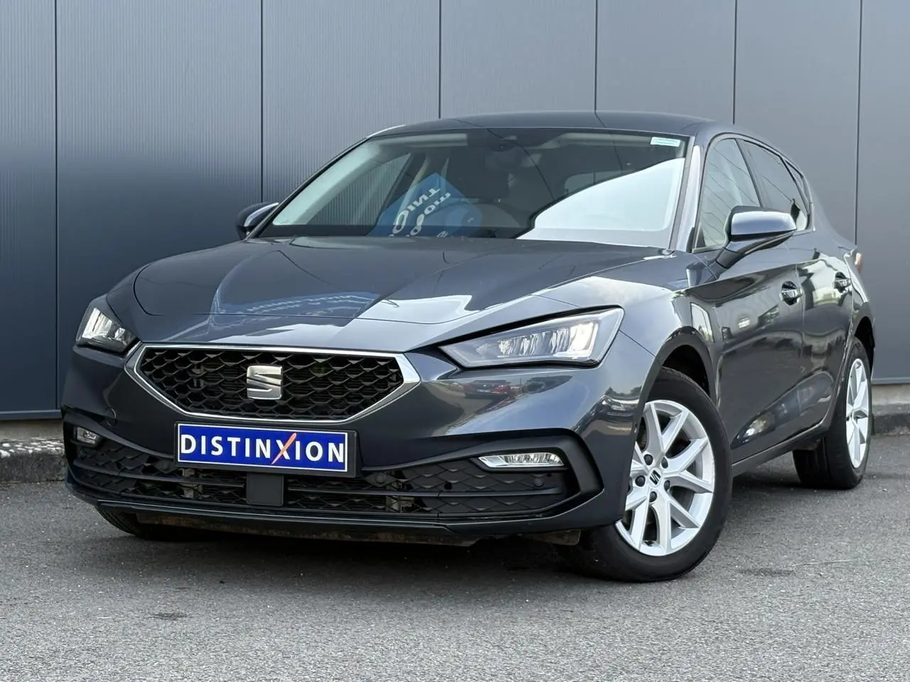 SEAT Leon 2024 gris magnétique en 3/4 avant droit, avec calandre hexagonale et jantes alliage 16 pouces.