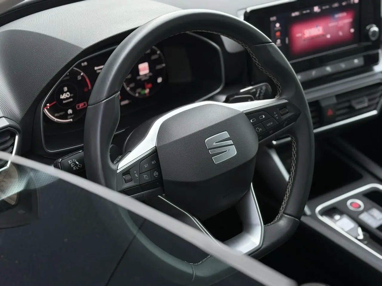 Volant cuir multifonction de la SEAT LEON 2.0 TDI 2024 vu de près avec tableau de bord numérique et console centrale moderne.