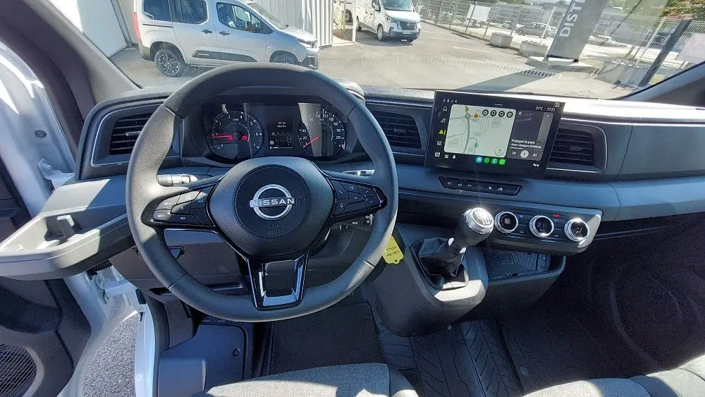 Vue intérieure du tableau de bord du Nissan Interstar Fourgon blanc 2025, volant multifonction et écran tactile avec navigation.