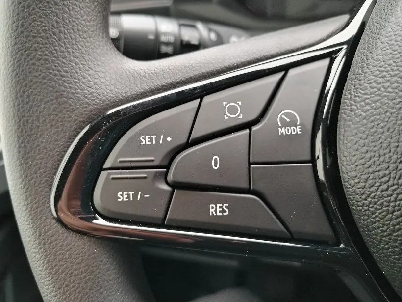 Gros plan sur les commandes noires au volant du Nissan Interstar Fourgon blanc, version 2026, avec boutons de réglage de vitesse et mode.