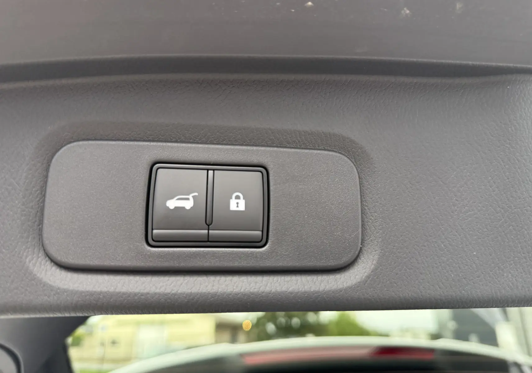 Boutons de commande pour ouverture et verrouillage du hayon sur le panneau intérieur du coffre d'un Nissan Qashqai blanc nacré 2025.