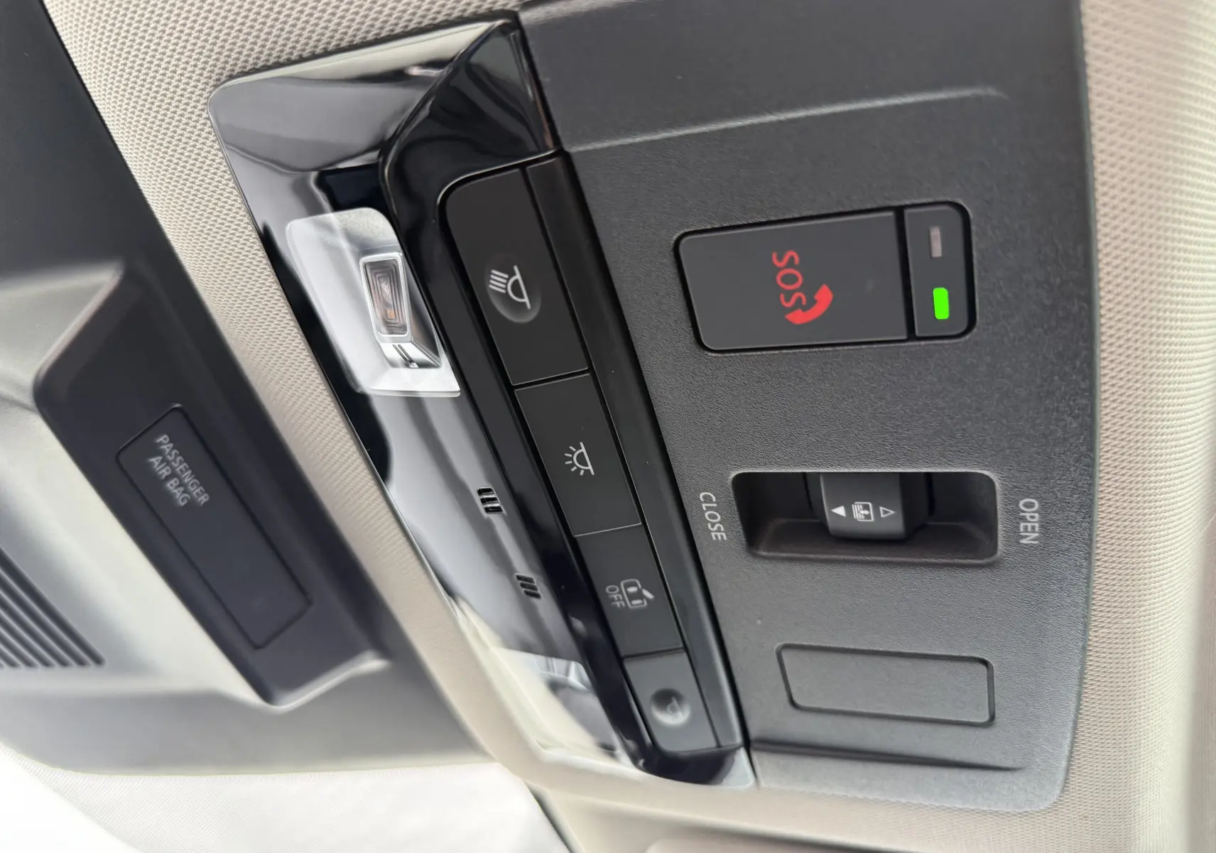 Vue en gros plan du panneau de commandes au plafond du Nissan Qashqai blanc nacré, avec bouton SOS et éclairage intérieur.