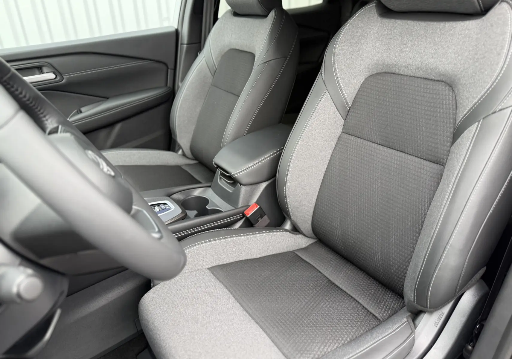 Intérieur du Nissan Qashqai 2025, vue rapprochée des sièges avant en tissu gris et noir avec coutures blanches.
