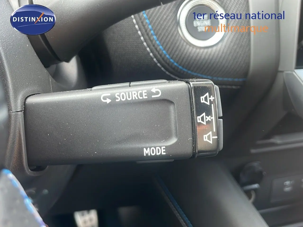 Gros plan sur la commande au volant du Renault Captur E-Tech hybride 2025 avec surpiqûres bleues sur cuir noir.