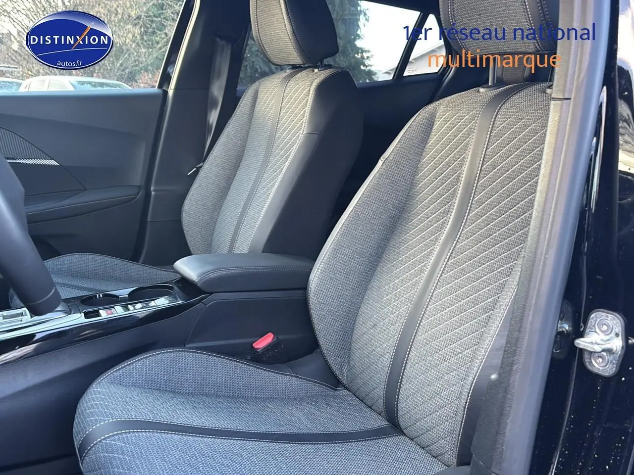 Vue intérieure côté conducteur sur les sièges avant gris texturés du Peugeot 2008 noir 2025, avec accoudoir central.