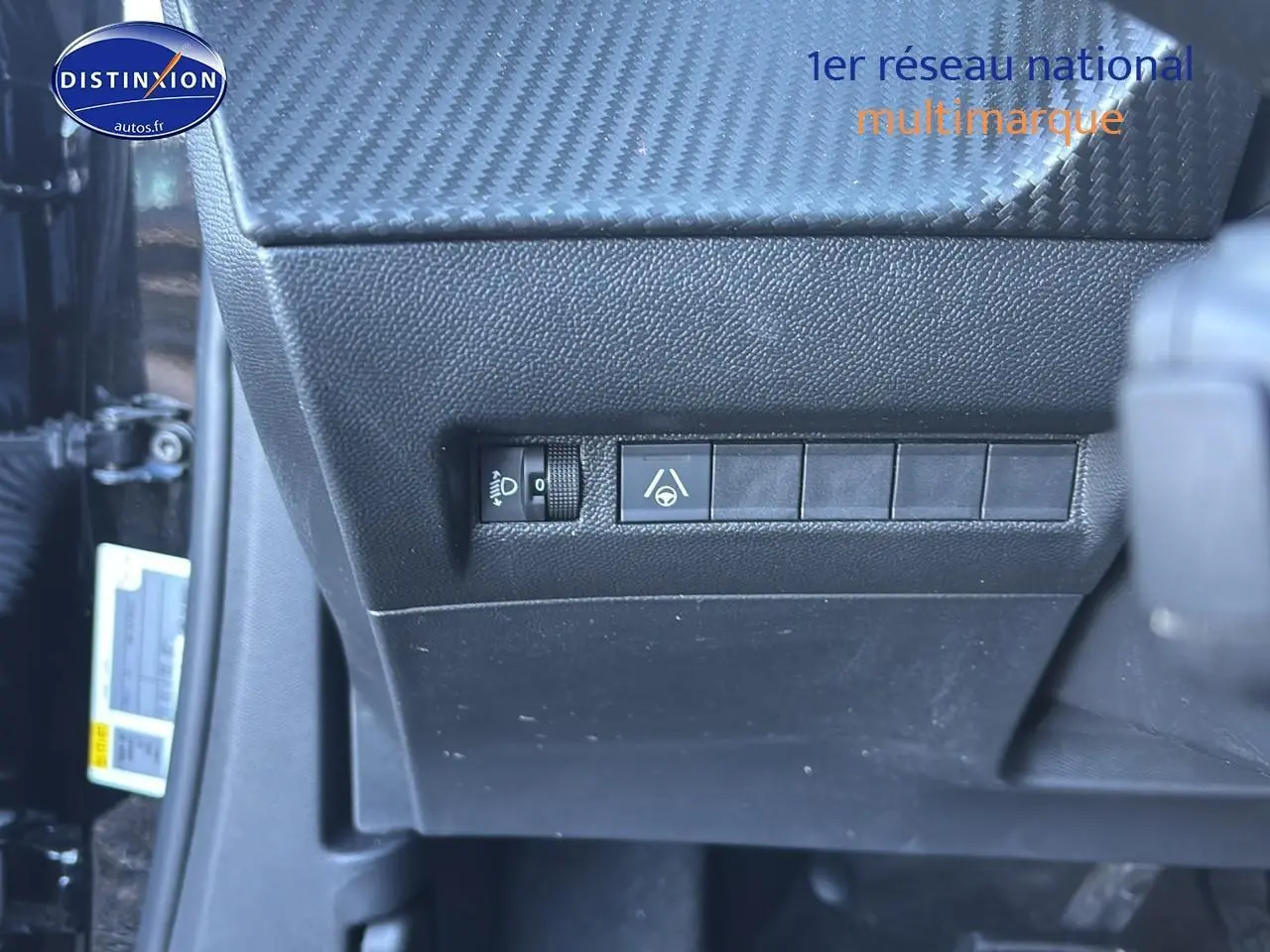Gros plan sur les commandes noires sous le tableau de bord côté gauche d’un Peugeot 2008 noir 2025.