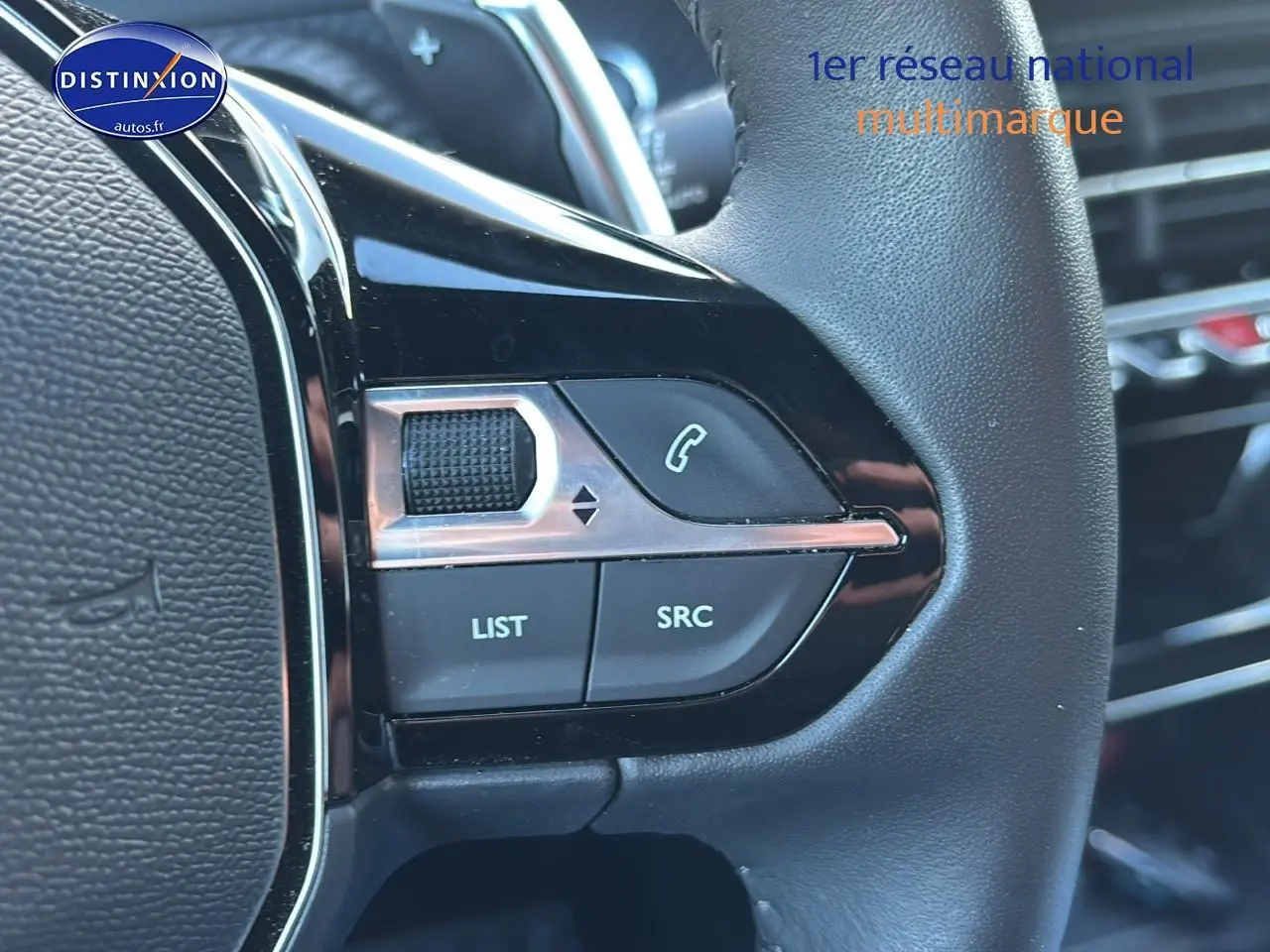 Gros plan sur les commandes du volant noir du Peugeot 2008 1.2 hybrid 145 allure e-dcs6, boutons multifonctions visibles.