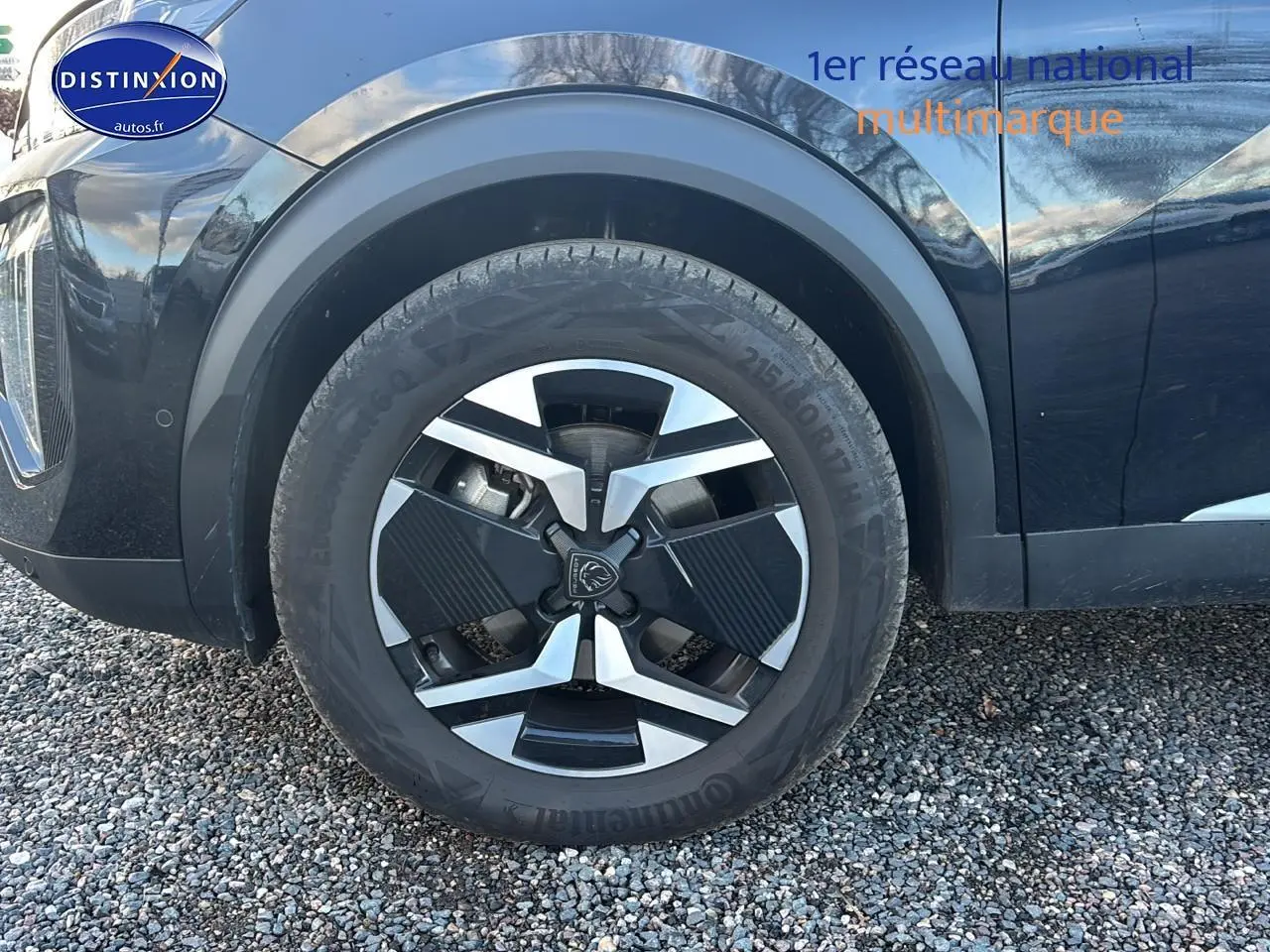 Gros plan sur la roue avant gauche noire du Peugeot 2008 1.2 hybrid 145 allure e-dcs6 avec jante alu distinctive.