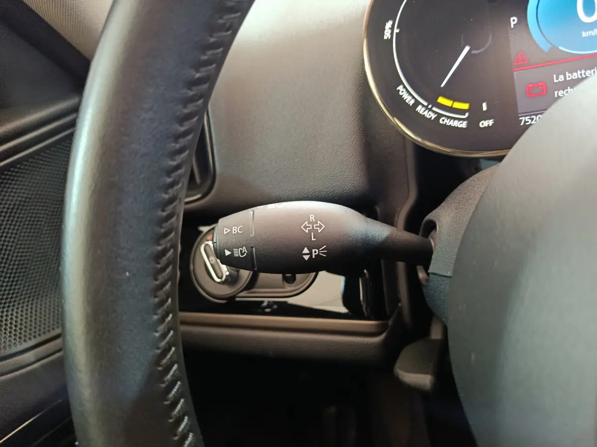 Gros plan sur la commande de clignotant à gauche du volant cuir dans l’habitacle du MINI Countryman blanc hybride rechargeable.