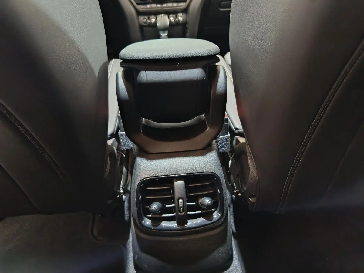 Vue intérieure arrière du MINI Countryman blanc, concentrée sur la console centrale avec bouches d'aération et accoudoir noir.