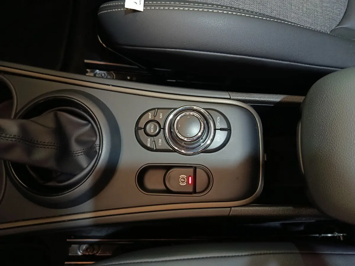 Vue rapprochée de la console centrale noire avec molette de commande et frein à main électrique du MINI Countryman blanc.
