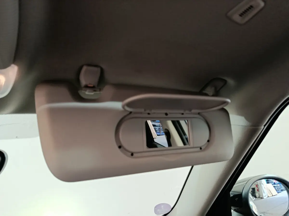 Détail du pare-soleil côté gauche avec miroir intégré dans l’habitacle du MINI Countryman blanc hybride rechargeable.
