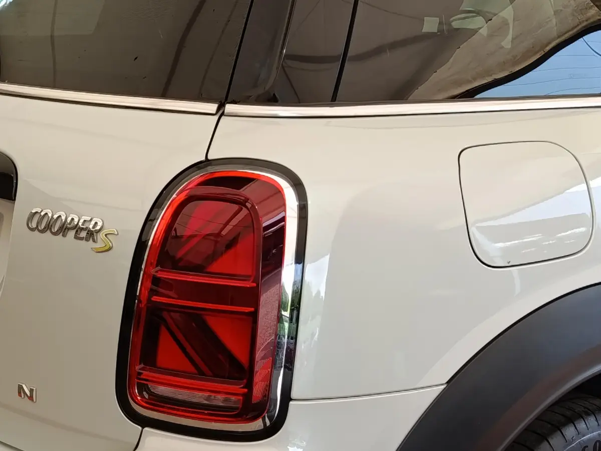 Gros plan sur le feu arrière gauche rouge d’un MINI Countryman blanc avec logo Cooper S visible.