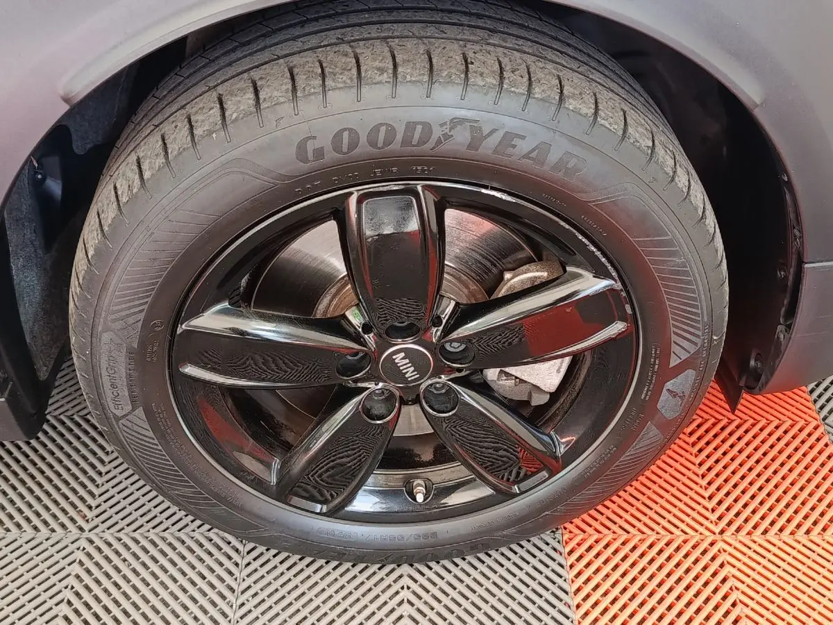 Gros plan sur la roue avant droite noire brillante d'une MINI Countryman blanche, pneu Goodyear visible.