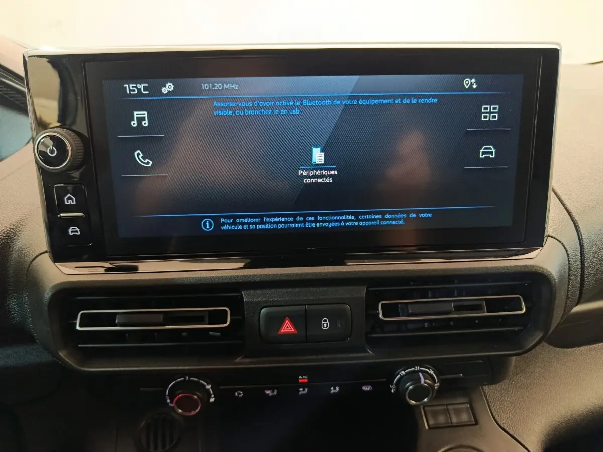 Écran tactile central du tableau de bord du Peugeot Partner 2025 avec commandes de climatisation et boutons de sécurité.