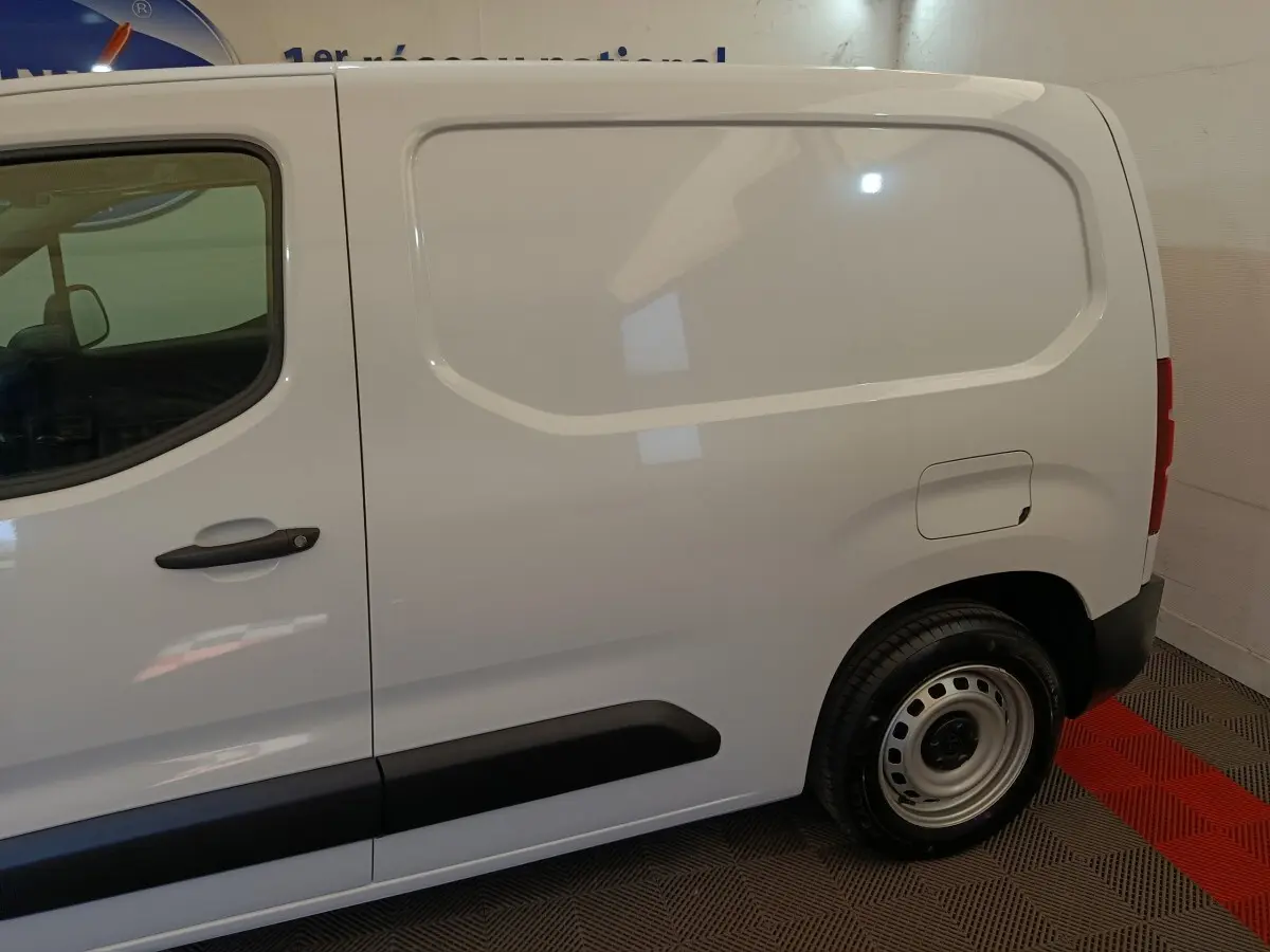 Vue de profil côté droit du Peugeot Partner blanc 2025, montrant la porte latérale pleine et la roue arrière acier.