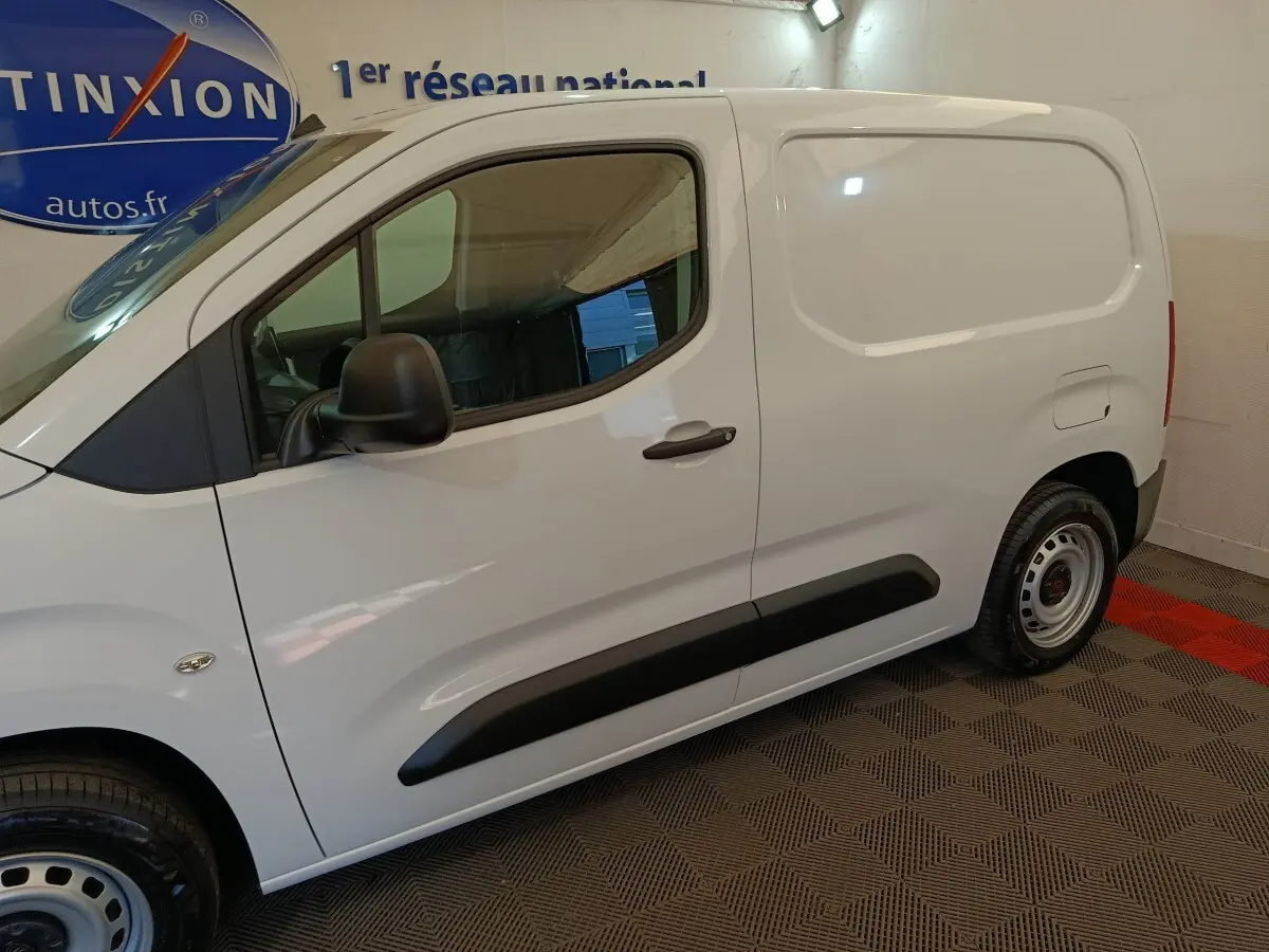 Vue de profil côté gauche du Peugeot Partner blanc, fourgon compact avec porte latérale pleine et rétroviseur noir.