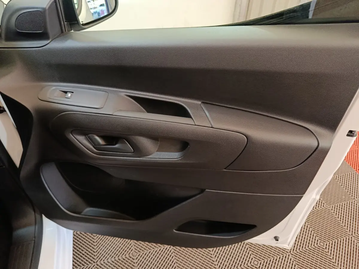 Vue intérieure côté gauche de la porte avant noire du Peugeot Partner blanc, avec poignée et commande de fenêtre.