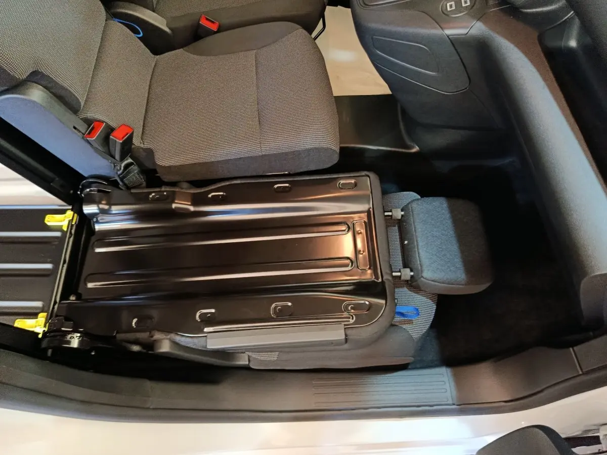 Vue plongeante sur le siège avant droit relevé du Peugeot Partner blanc, montrant la structure métallique et l'assise grise.
