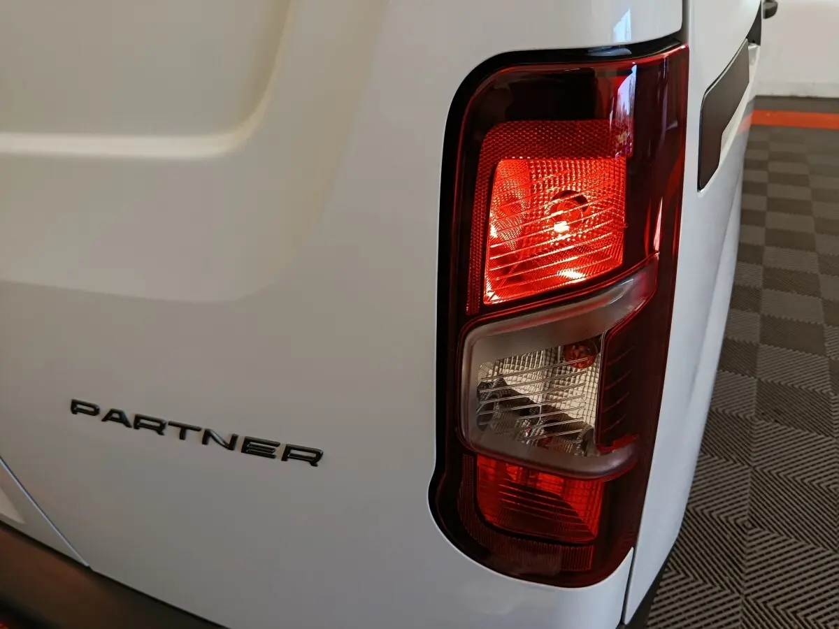 Gros plan sur le feu arrière droit et le logo PARTNER d’un utilitaire Peugeot Partner blanc, vue arrière droite.