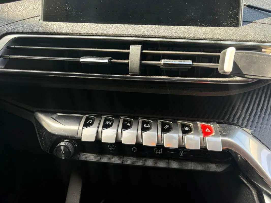 Détail de la console centrale avec les commandes piano chromées et la sortie d’air du Peugeot 3008 noir 2021.