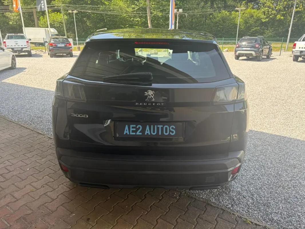 Vue arrière d'un Peugeot 3008 noir 2021, mettant en valeur les feux arrière teintés et le logo central sur un parking extérieur.
