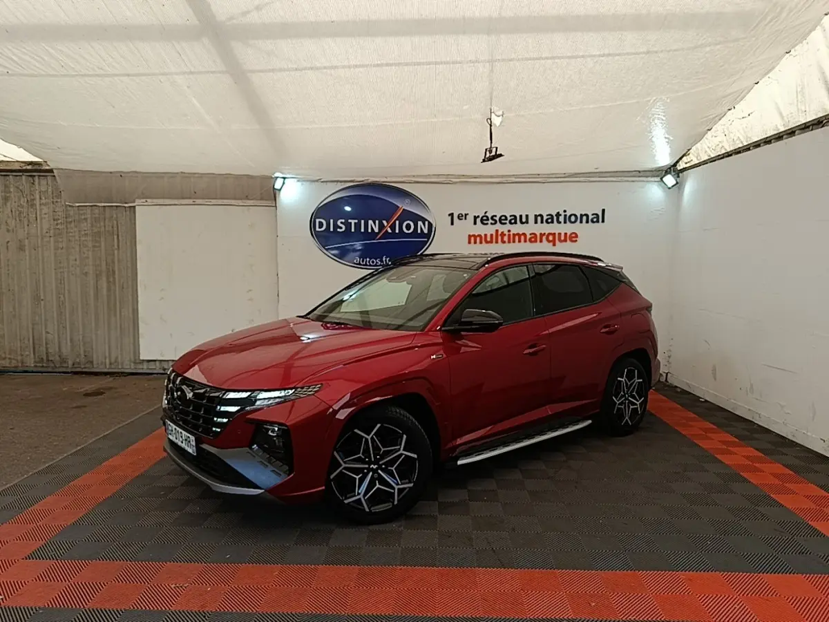 Hyundai Tucson rouge vue 3/4 avant droit en intérieur, avec jantes alliage noires et toit noir.
