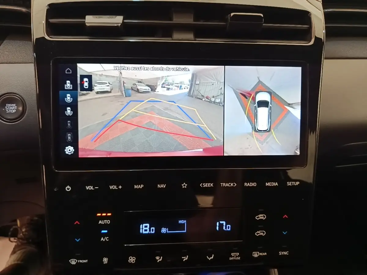 Écran tactile central montrant la caméra 360° et l’aide au stationnement du Hyundai Tucson rouge, vue intérieure.