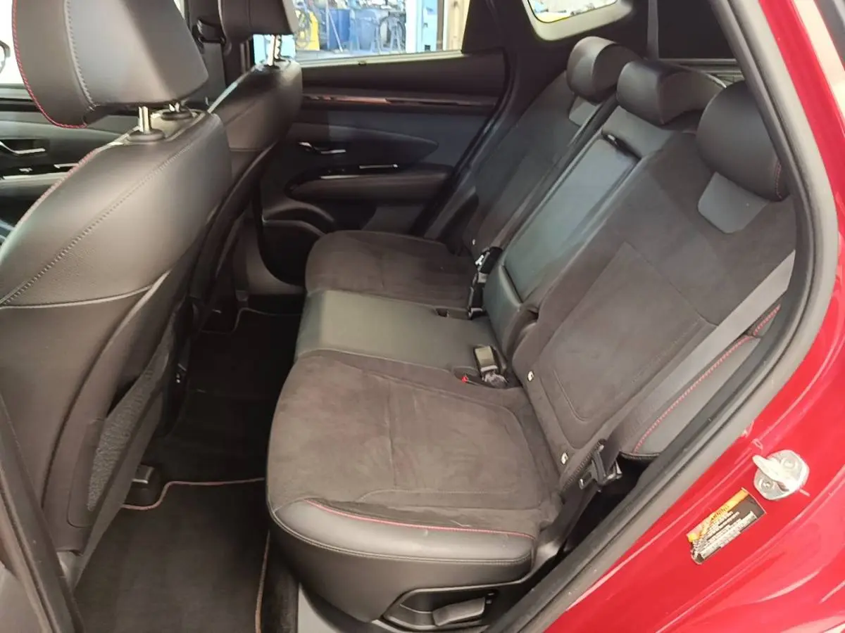 Vue intérieure arrière côté droit du Hyundai Tucson rouge 2022, sièges noirs avec surpiqûres rouges.
