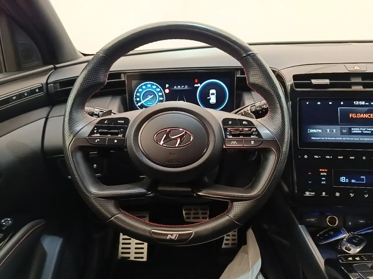 Vue intérieure centrée sur le volant cuir perforé N Line et tableau de bord numérique du Hyundai Tucson 2022.