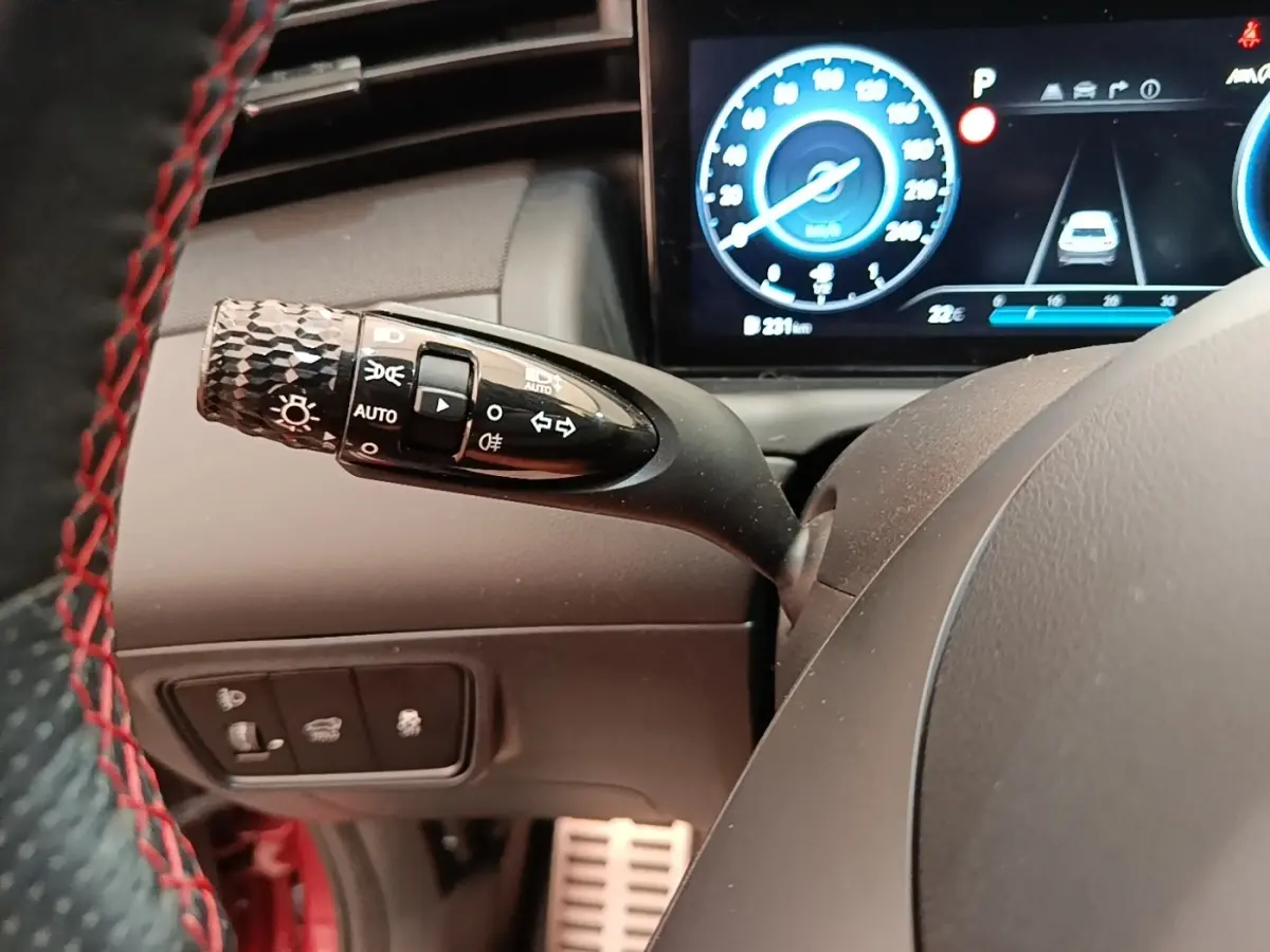 Gros plan sur la manette des feux et clignotants côté gauche du volant du Hyundai Tucson 2022, tableau de bord digital visible.