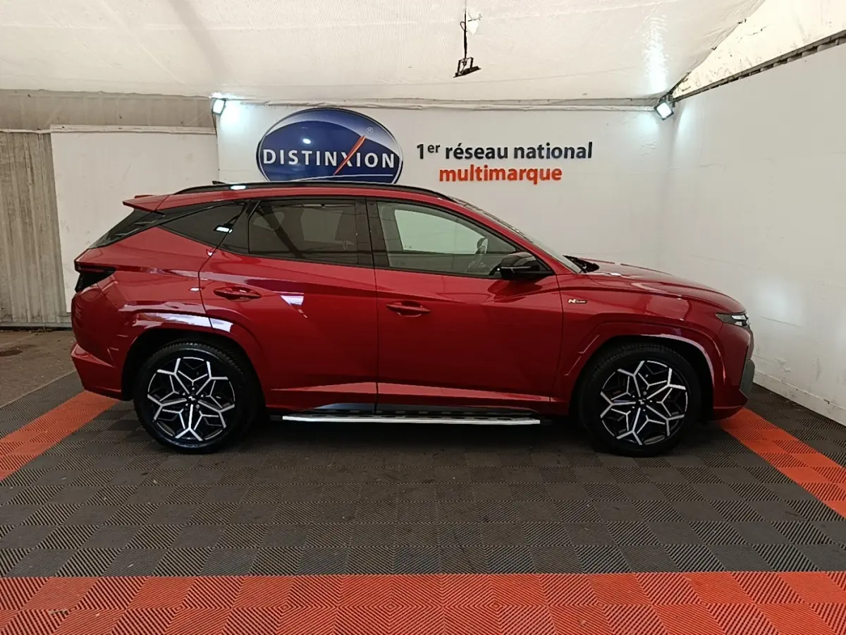 Hyundai Tucson rouge vue de profil côté gauche, avec jantes noires et argentées au design distinctif N Line.