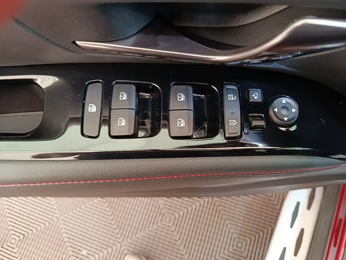 Gros plan sur les commandes de lève-vitres et rétroviseurs côté conducteur du Hyundai Tucson rouge, finition N Line.