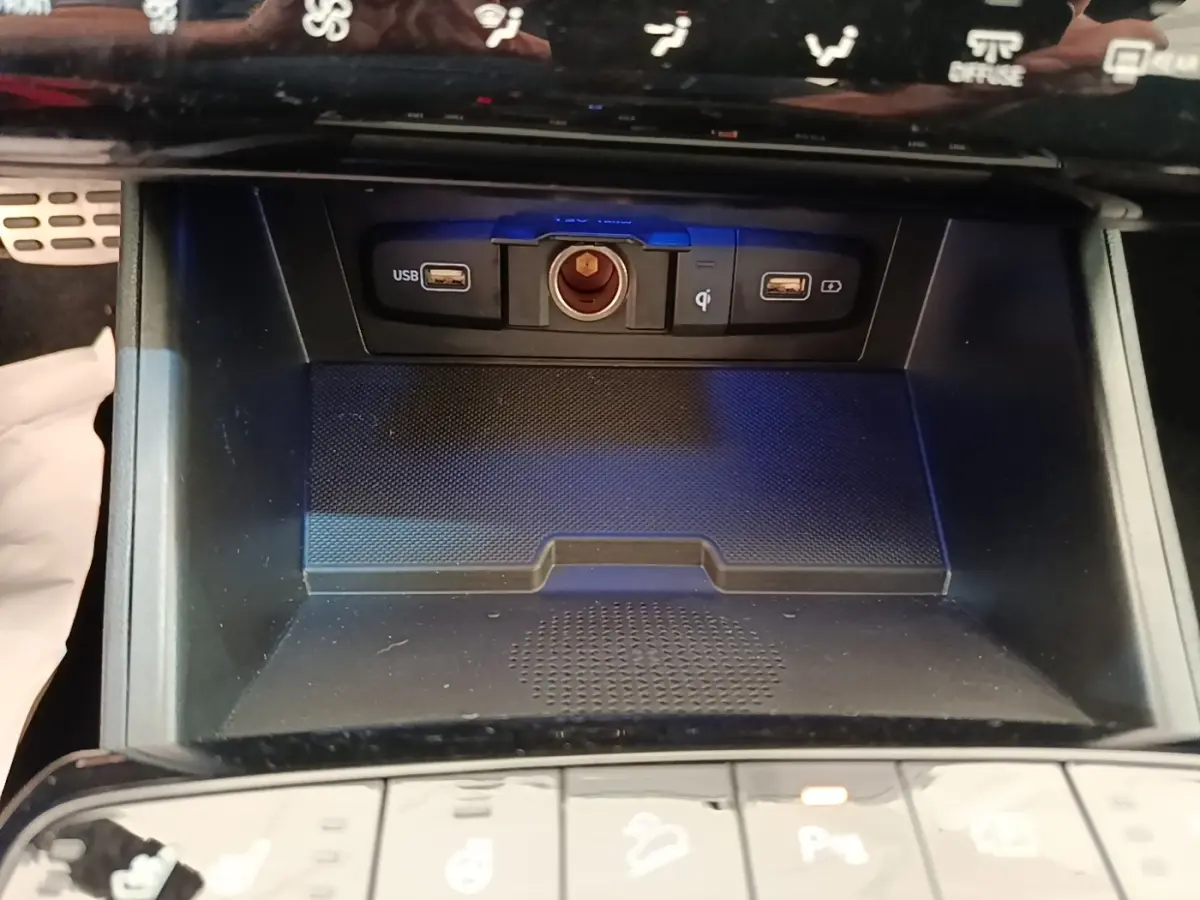 Gros plan sur la console centrale du Hyundai Tucson 2022, montrant ports USB, prise 12V et zone de recharge sans fil.