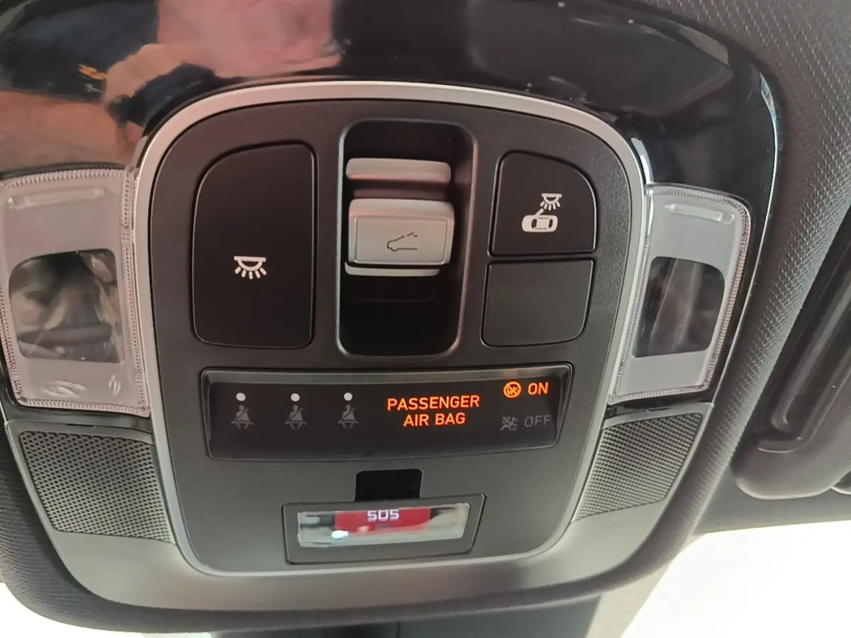Vue rapprochée du panneau de commandes au plafond du Hyundai Tucson rouge, avec indicateur airbag passager allumé.