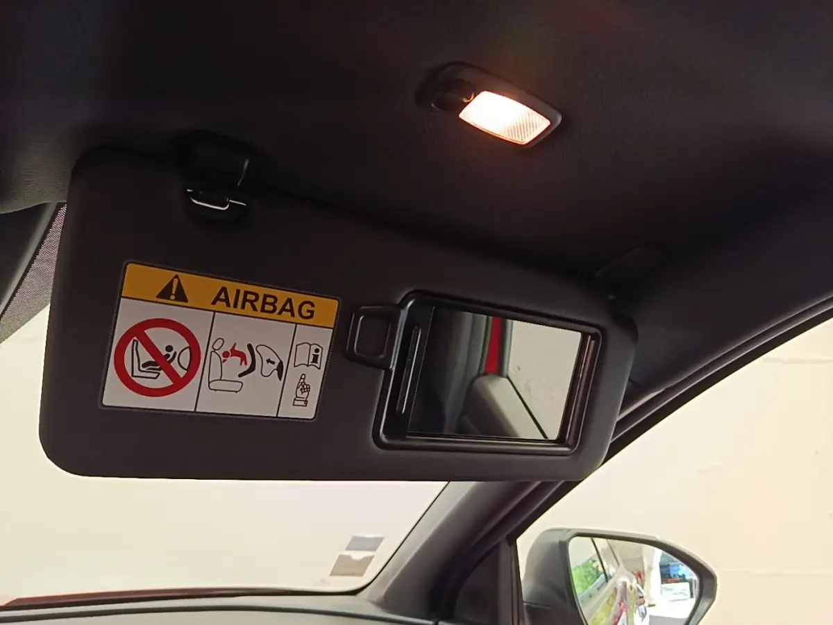 Détail du pare-soleil côté conducteur avec miroir intégré et avertissement airbag, intérieur noir du Hyundai Tucson rouge.