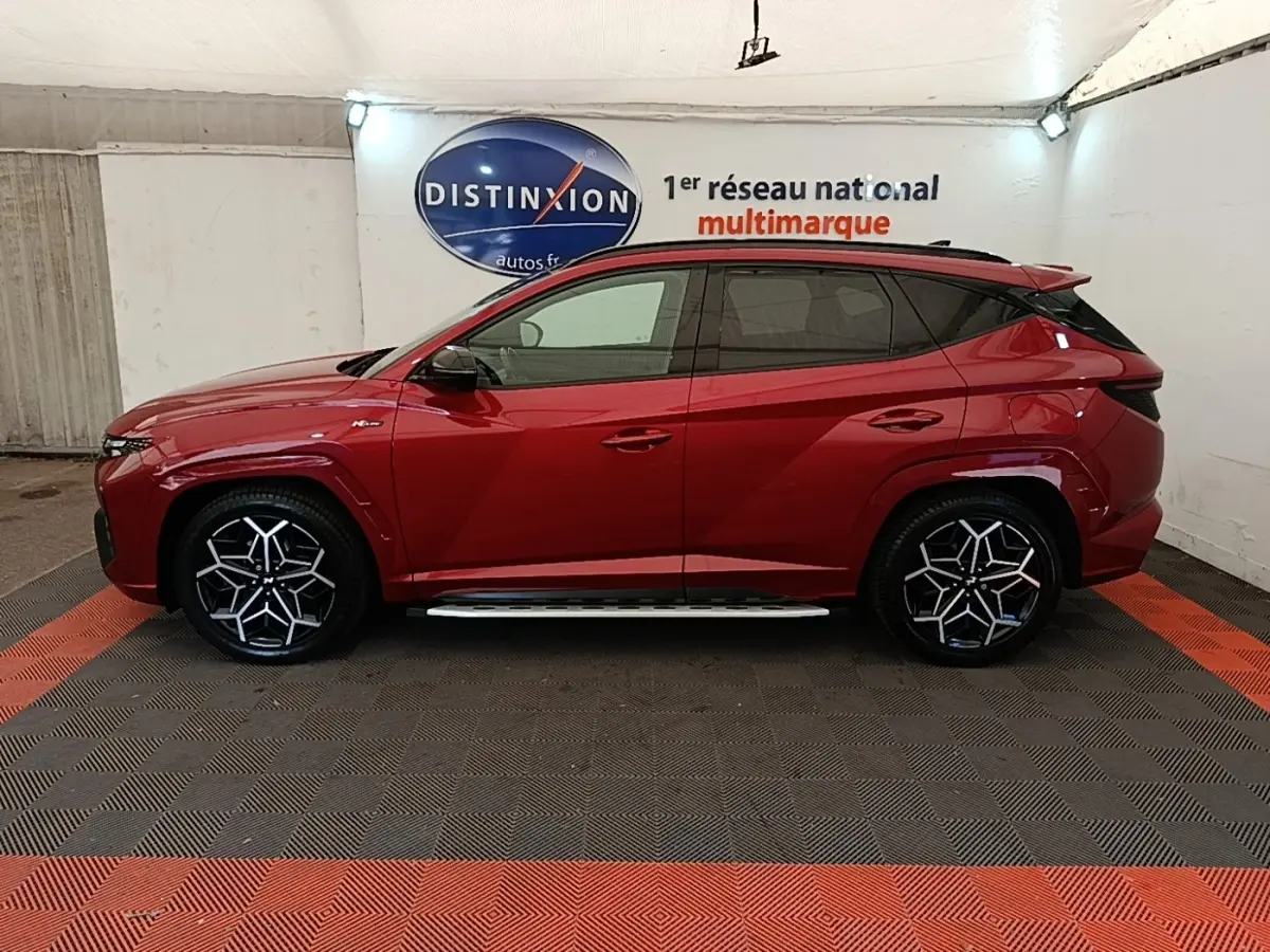 Hyundai Tucson rouge vue de profil côté gauche, avec jantes noires et détails N Line visibles.