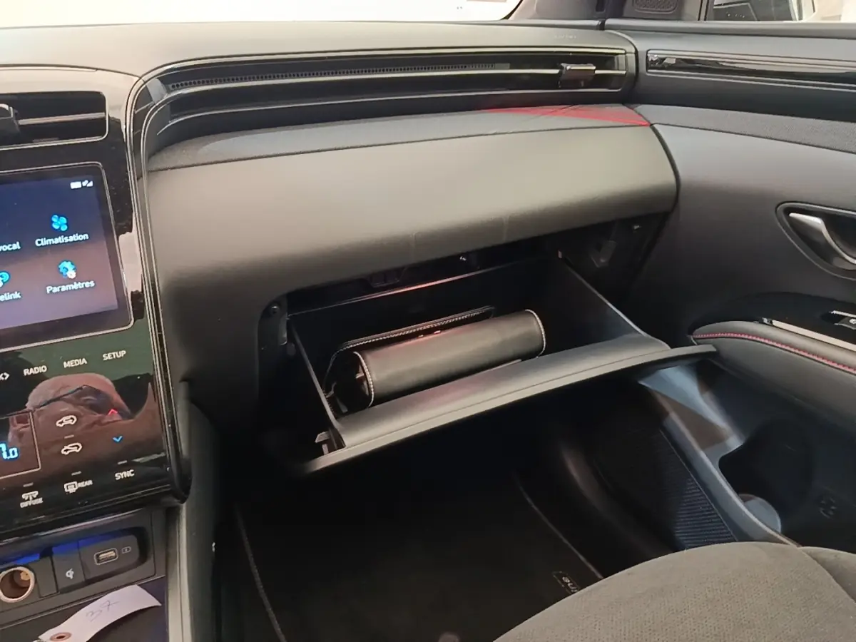 Intérieur du Hyundai Tucson 2022, vue côté passager sur la boîte à gants ouverte avec un étui noir à l'intérieur.