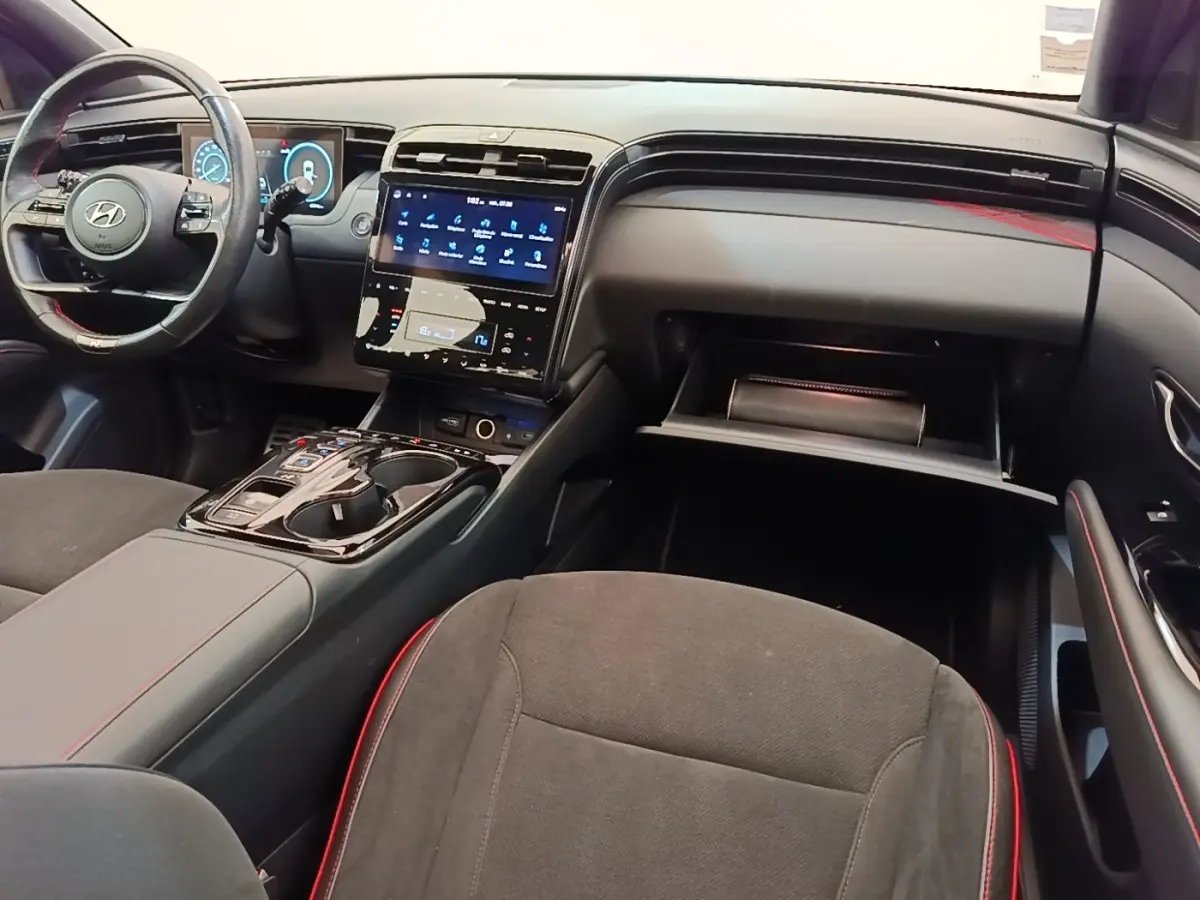 Intérieur noir et rouge du Hyundai Tucson 2022, vue de côté droit sur le tableau de bord et console centrale tactile.