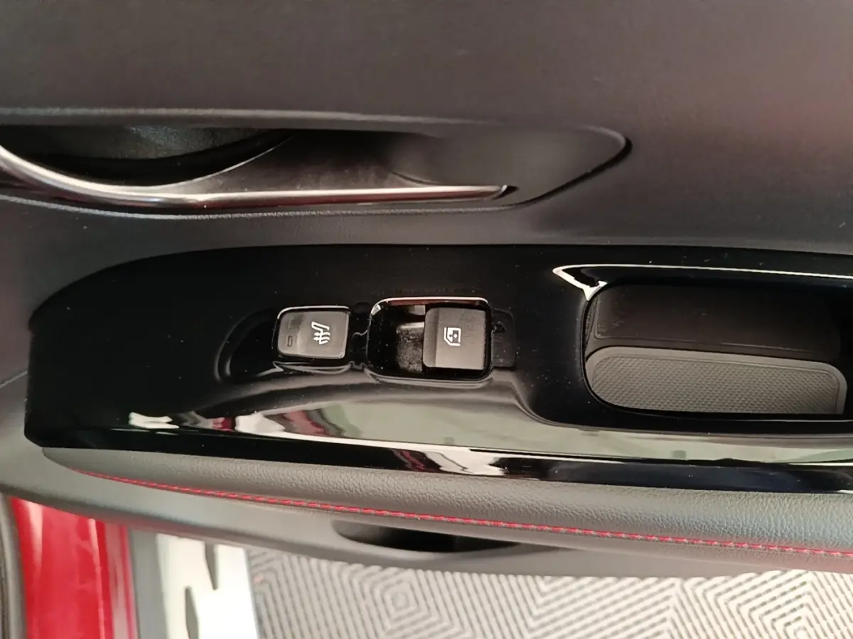Gros plan sur la commande de lève-vitre et siège chauffant côté conducteur d’un Hyundai Tucson rouge.