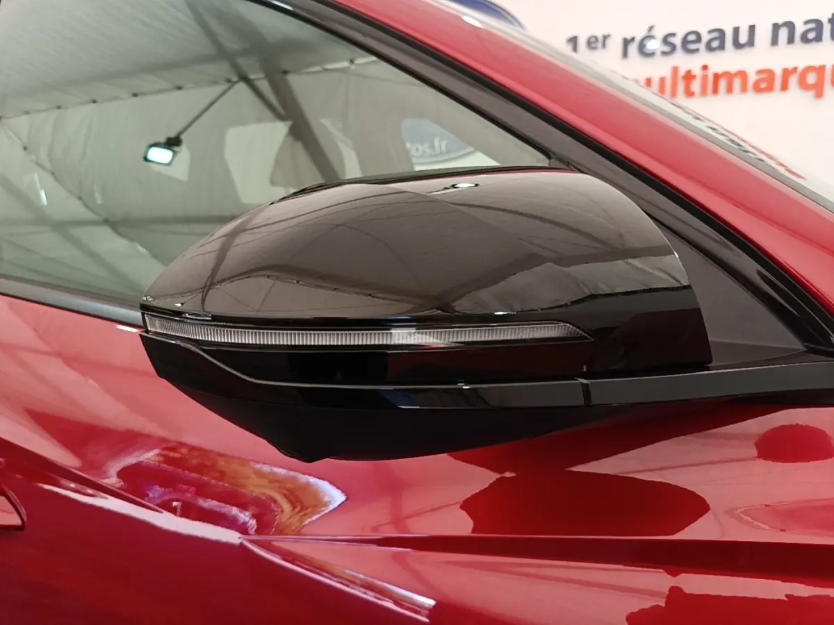 Rétroviseur latéral droit noir brillant sur Hyundai Tucson rouge, vue rapprochée sur la porte avant.