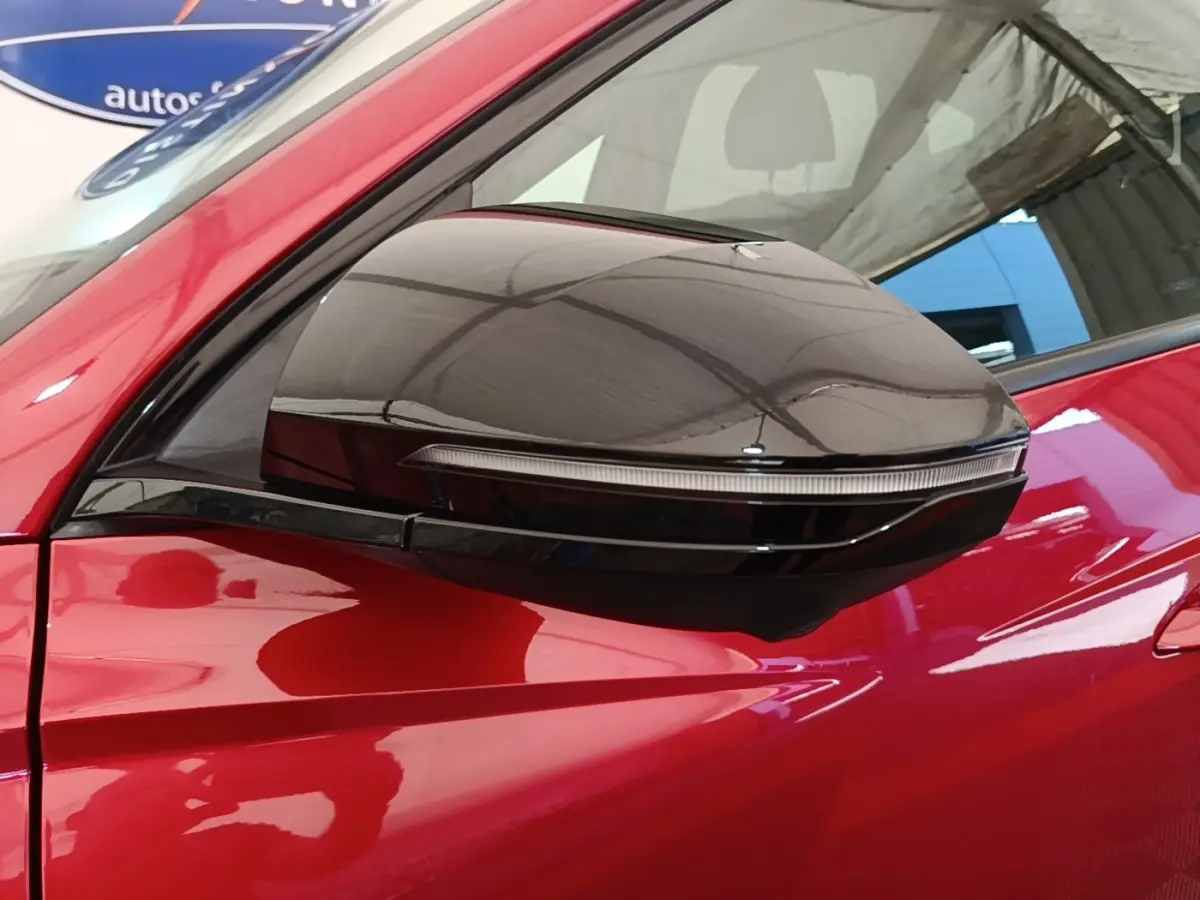 Gros plan sur le rétroviseur droit noir brillant du Hyundai Tucson rouge, mettant en valeur le clignotant intégré.
