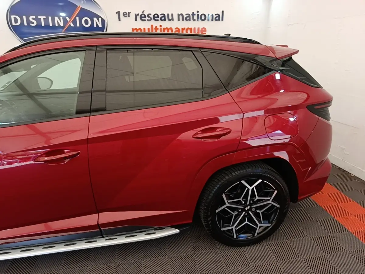 Vue latérale droite du Hyundai Tucson rouge 2022 avec jante alliage noire et détails de carrosserie anguleux.